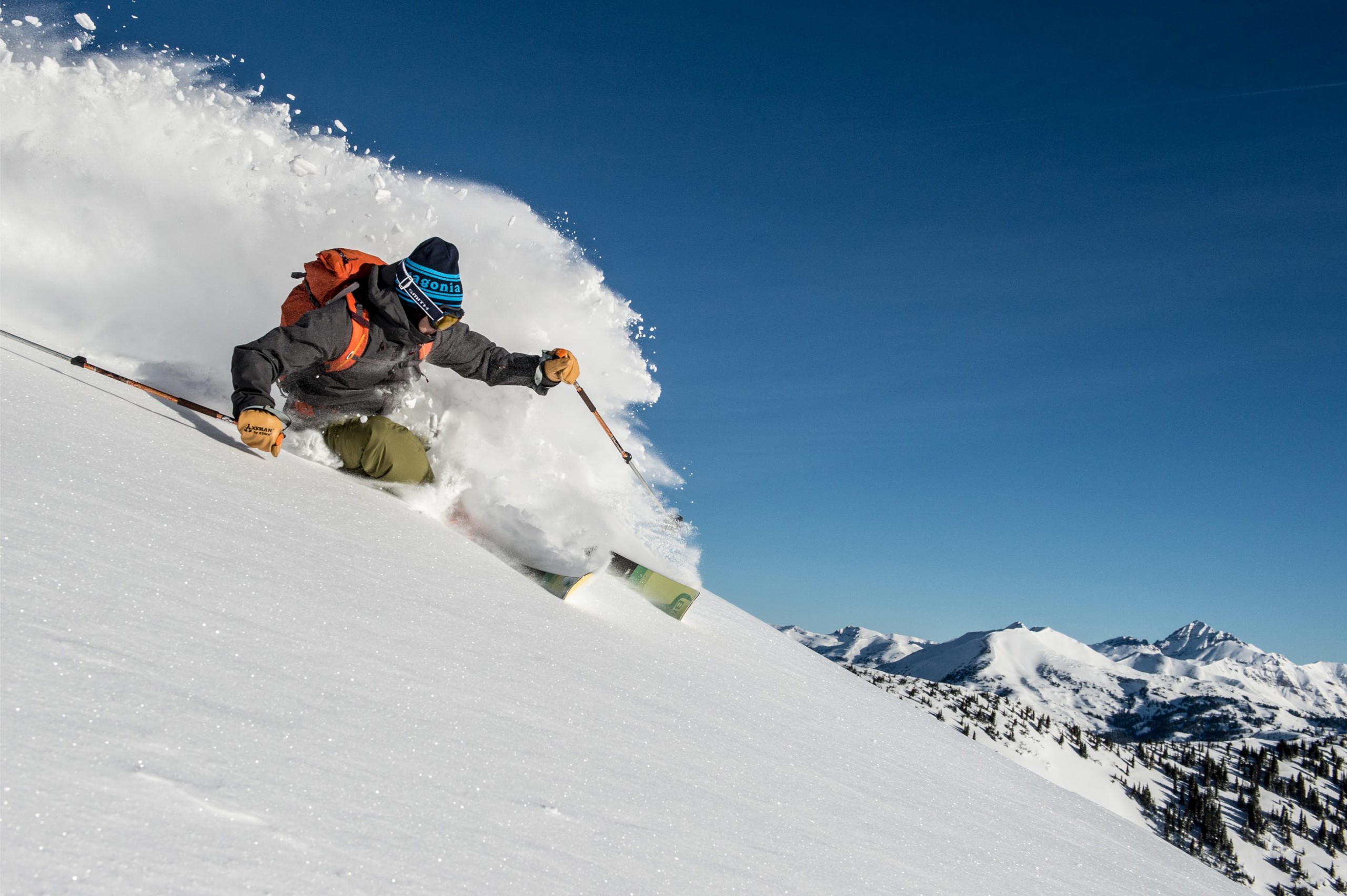 A skier carving to a stop near the top of a mountain.