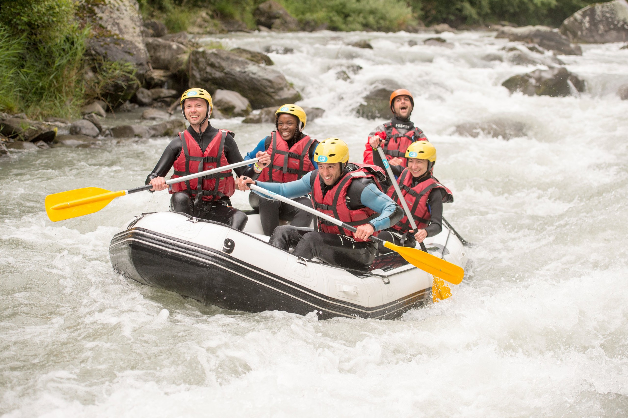 A group of people on a raft going through a rapid.