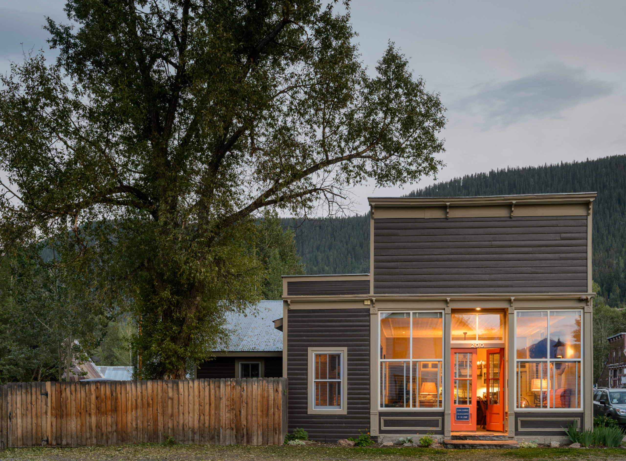 A historical western building sits at the end of the lane, with the light on and red door open. It i
