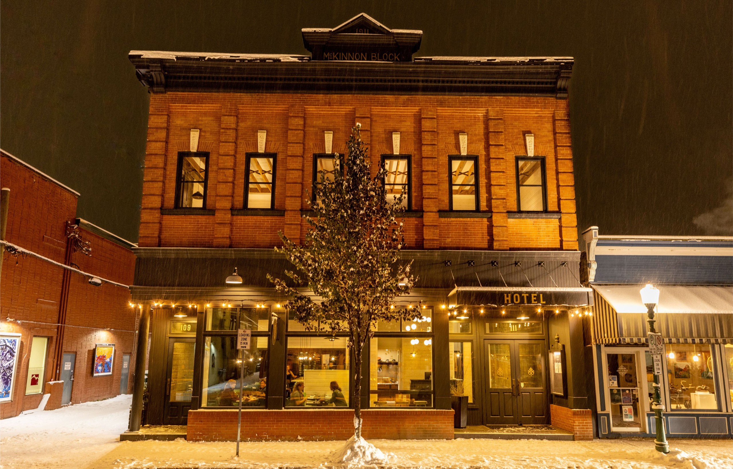 The front facade of Eleven's Revelstoke lodge at night in the winter time.